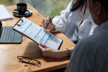 Woman guiding a man to fill the health insurance form