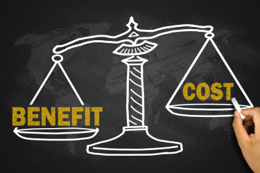 A hand draws a balance scale on a chalkboard, with “Benefit” on the lower left pan and “Cost” on the higher right pan.