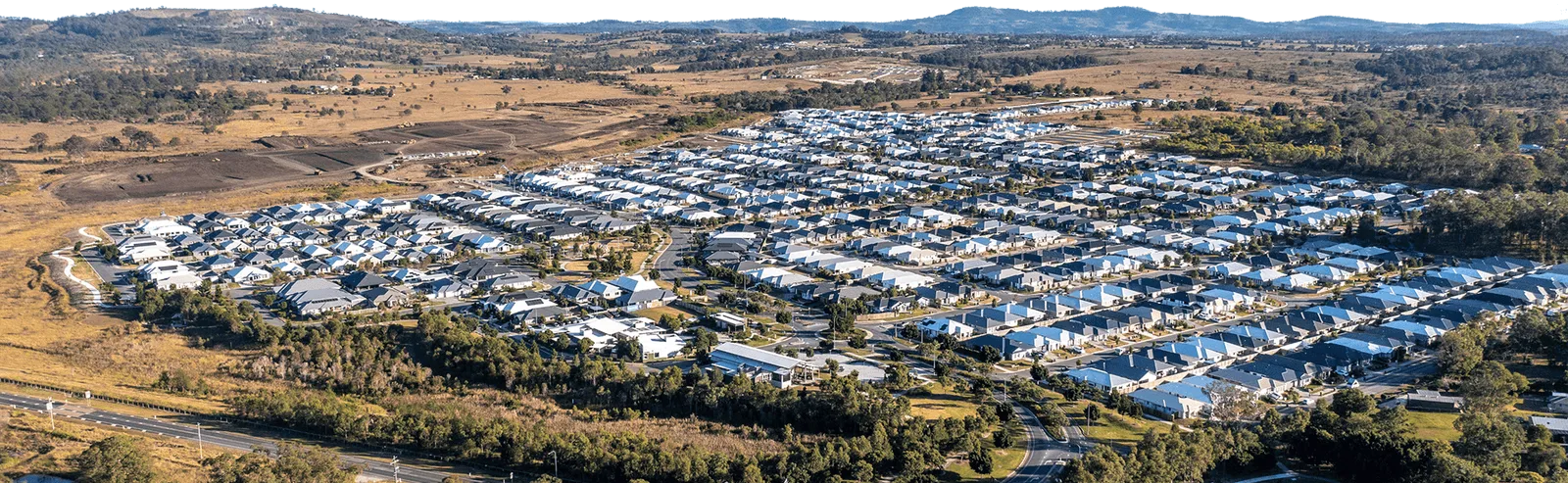 Aerial view of buildings and houses surrounded by trees and paddocks 