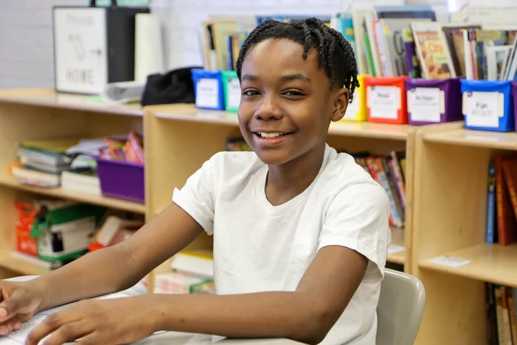 Student smiling at desk in classroom