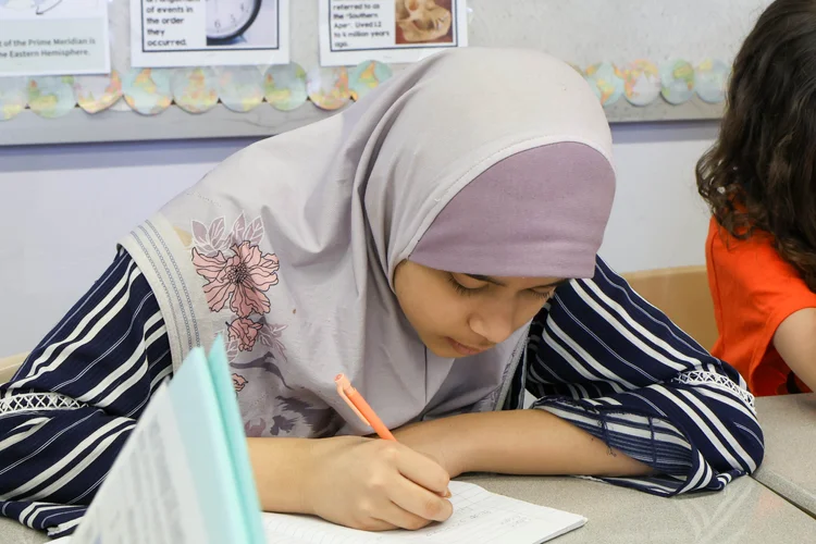 Student writing in notebook during a classroom lesson