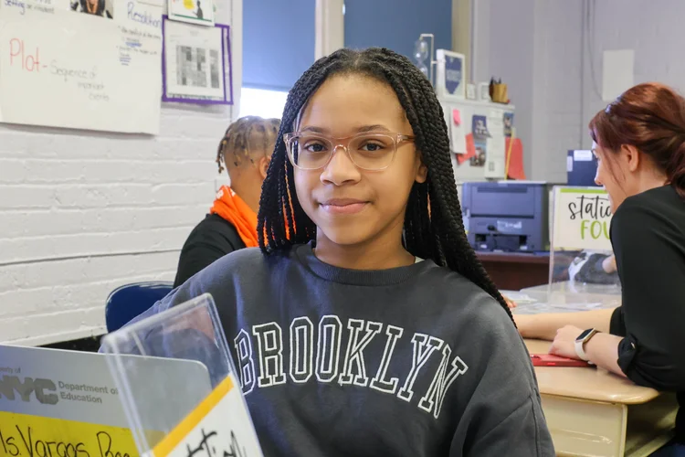 Student smiling at desk in elementary school classroom