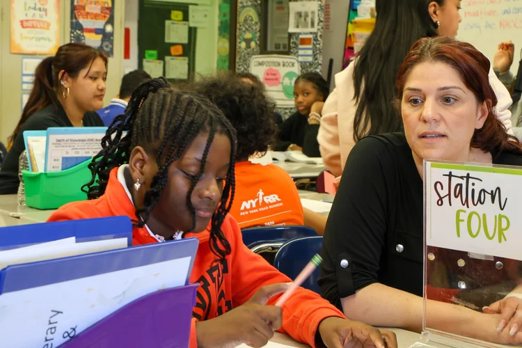 Teacher helping a student work at classroom Station Four