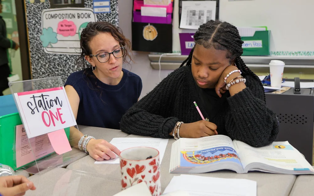 Teacher works one-on-one with student at Station One reading activity