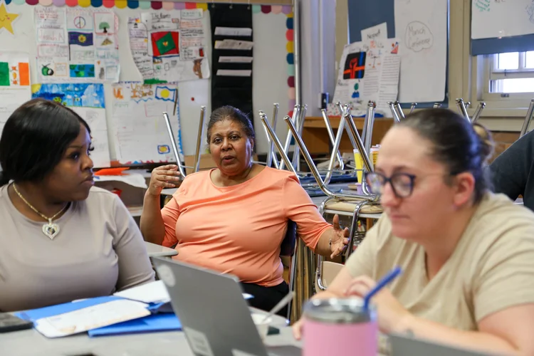 Three adults in discussion during a classroom meeting or training