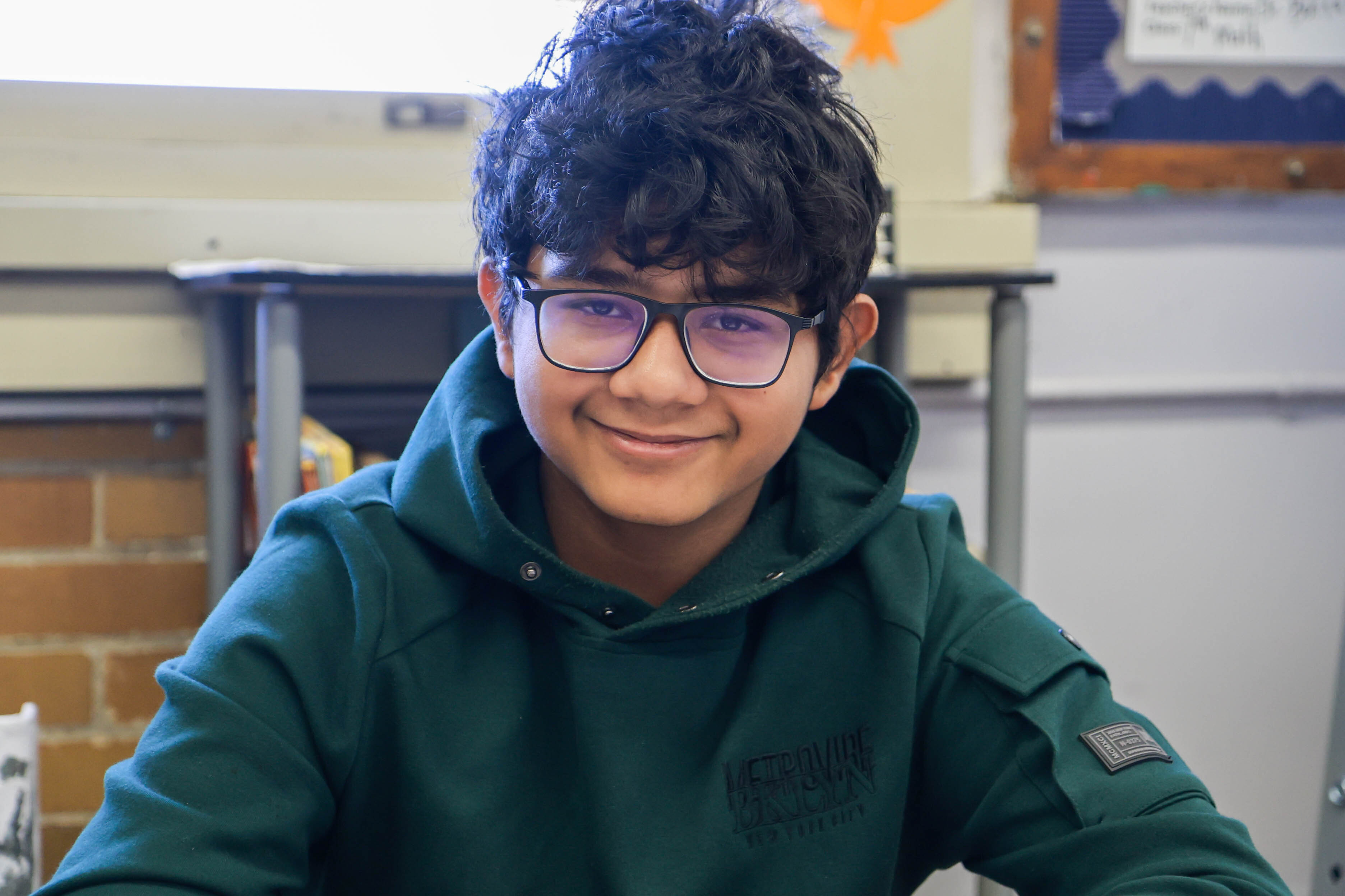 Smiling student wearing glasses seated in a classroom