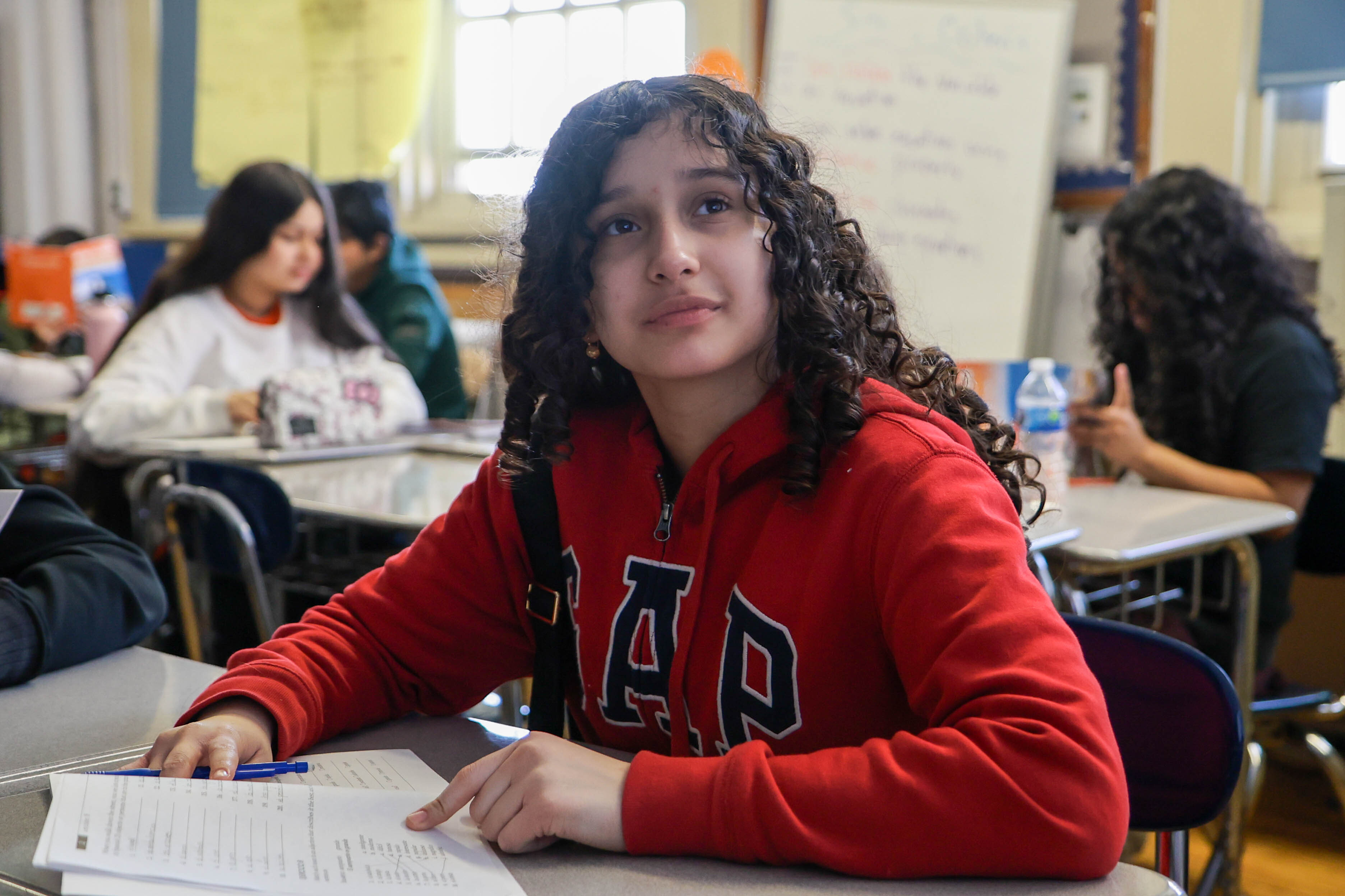 Student sitting at classroom desk with paper and pen