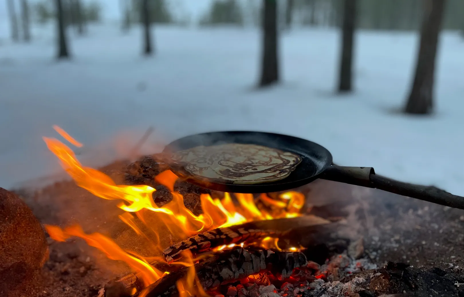 Nuotiolla paistumassa lettuja sähköpyöräsafarin päätteeksi
