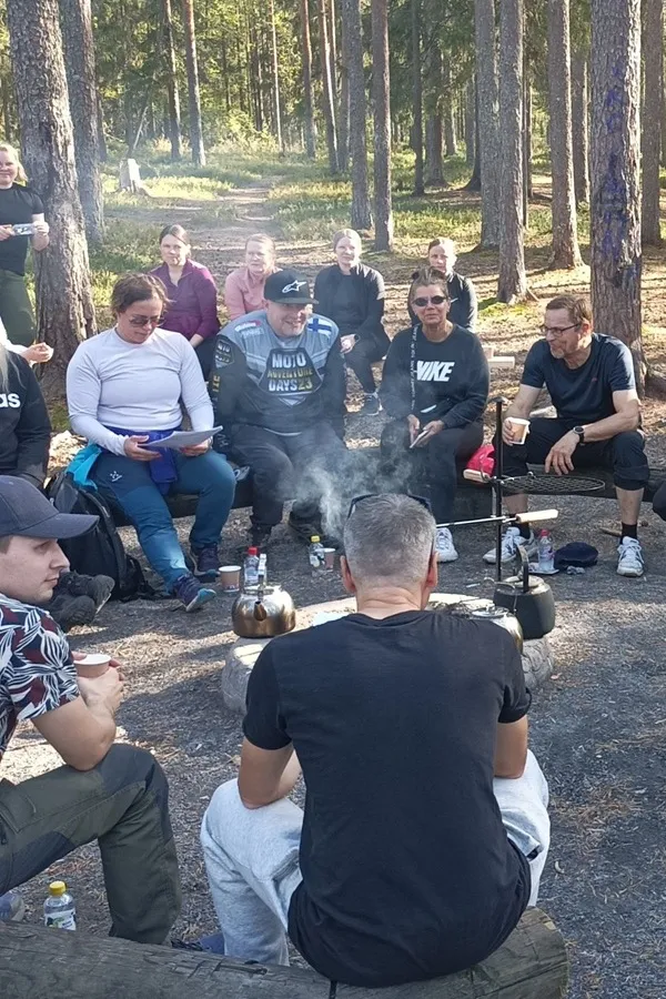 Ryhmä nuotion äärellä luonnossa nauttimassa tulen lämmöstä