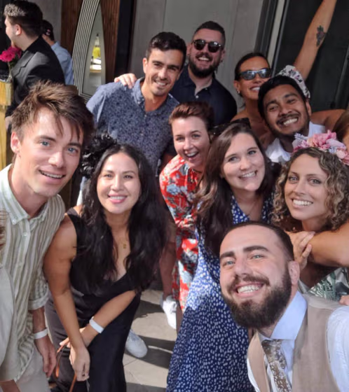 Smiling diverse group of friends posing together for a cheerful selfie outdoors.