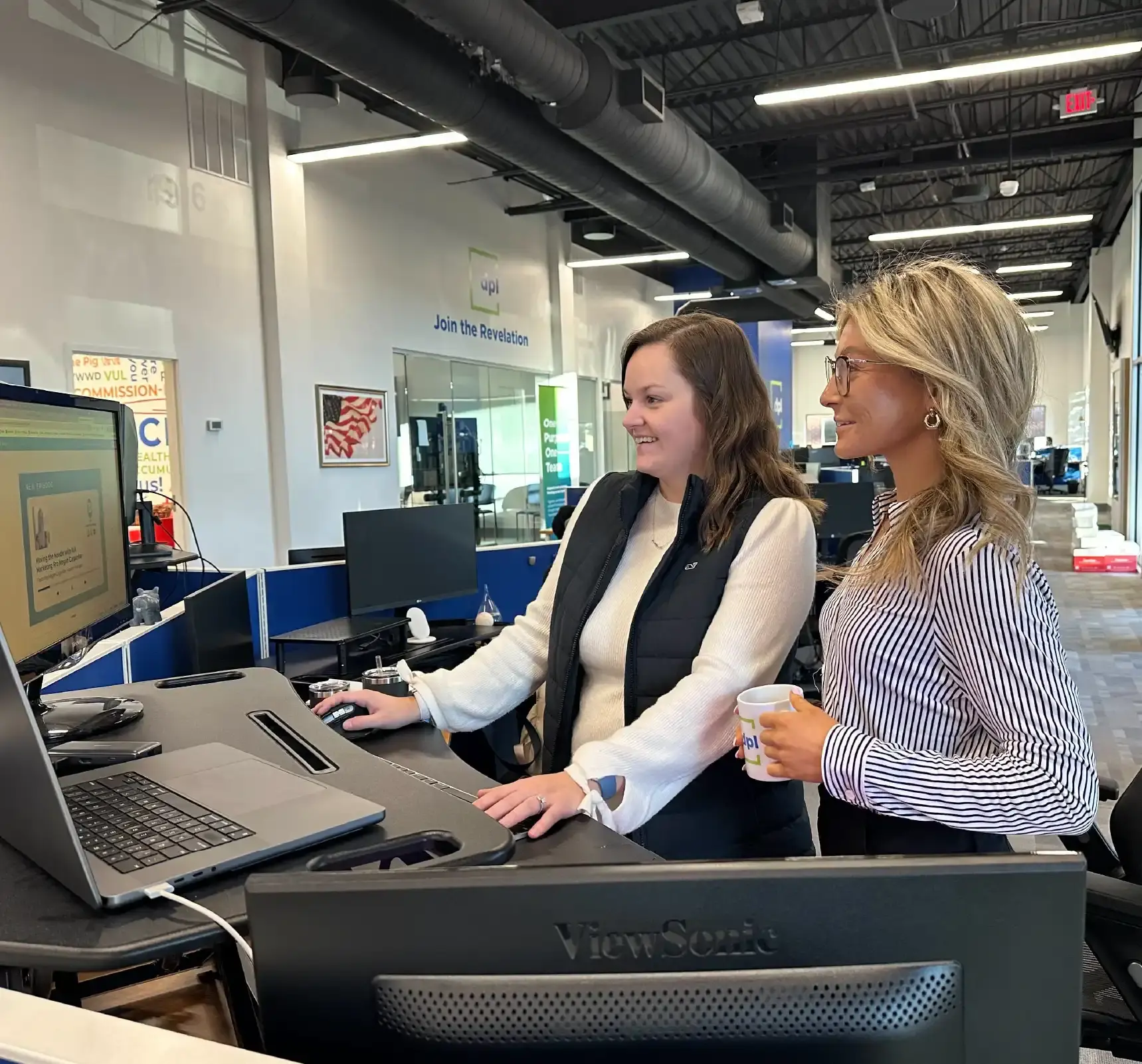 Two women smiling while working at computer.