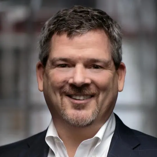 Man in suit smiling in professional portrait.