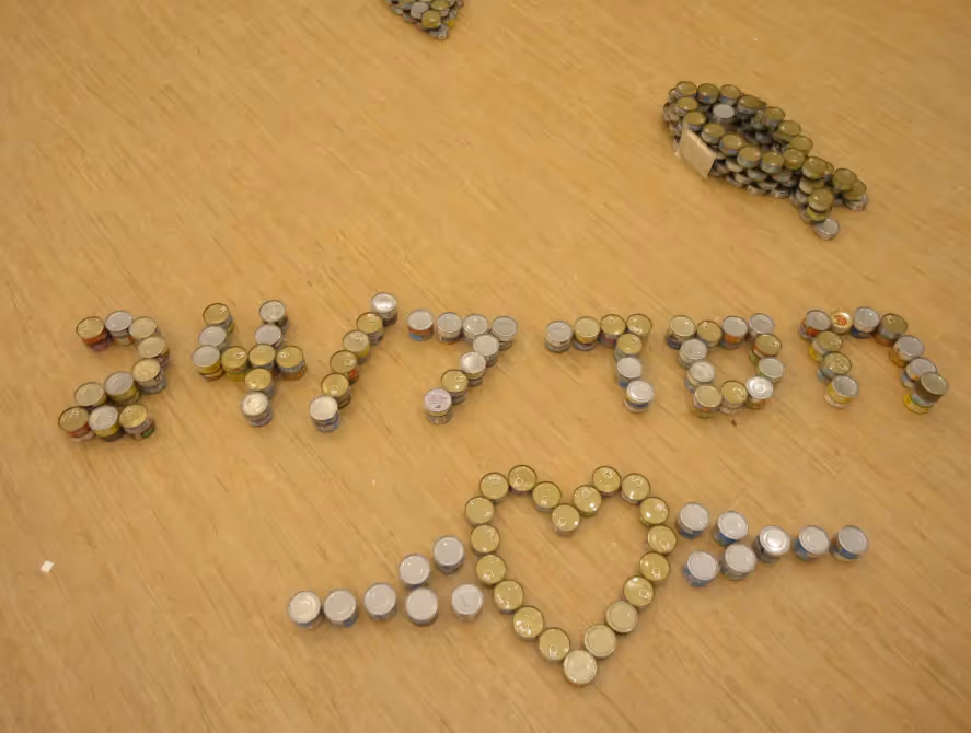 Donated tuna cans arranged to spell a message and form a heart during Chesed 24/7’s summer tuna drive supporting hospital chesed rooms