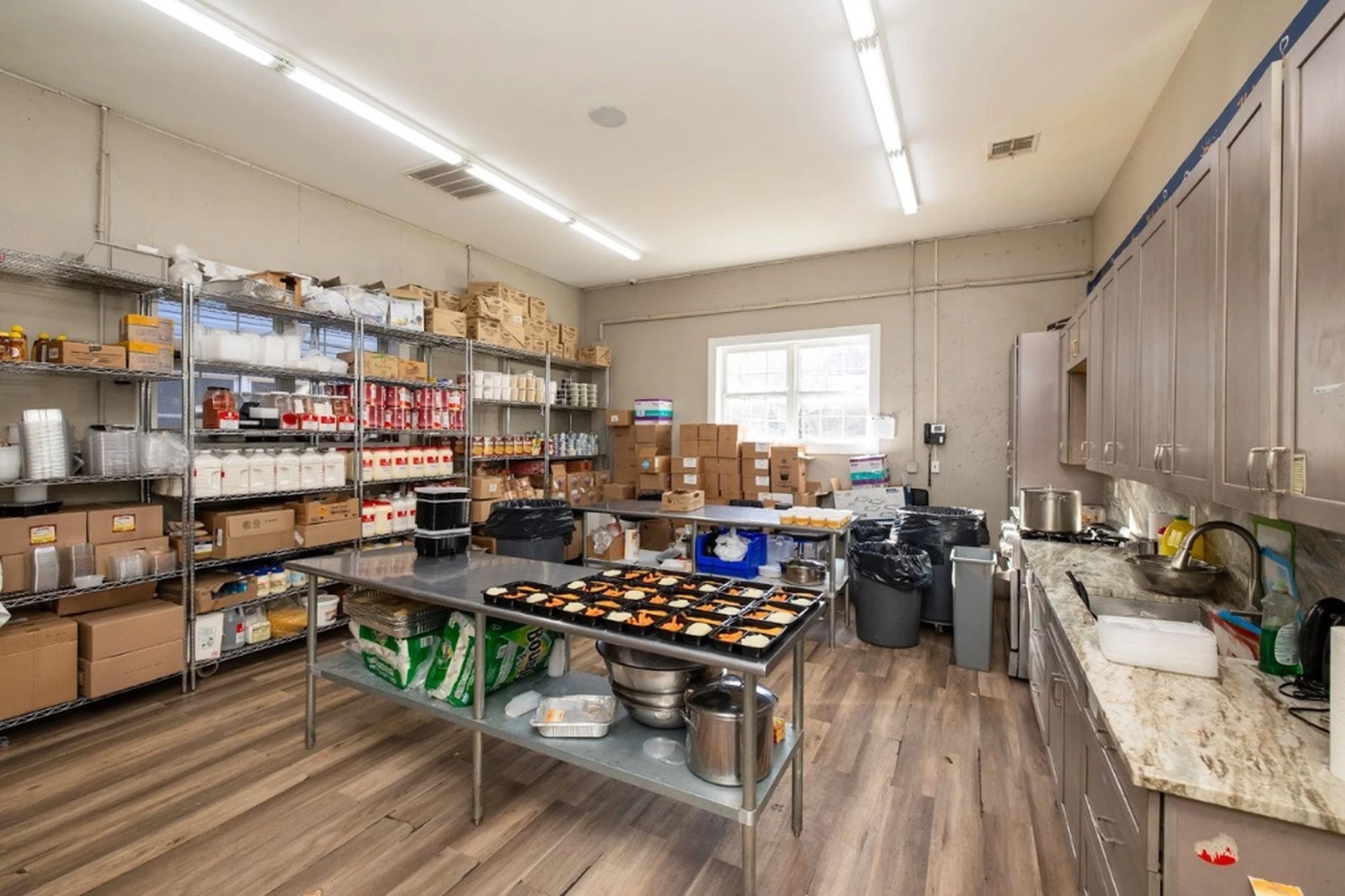 Chesed 24/7 commercial kitchen with stocked shelves of kosher ingredients and individual meal trays being prepared for daily hospital delivery to patients across New York and New Jersey