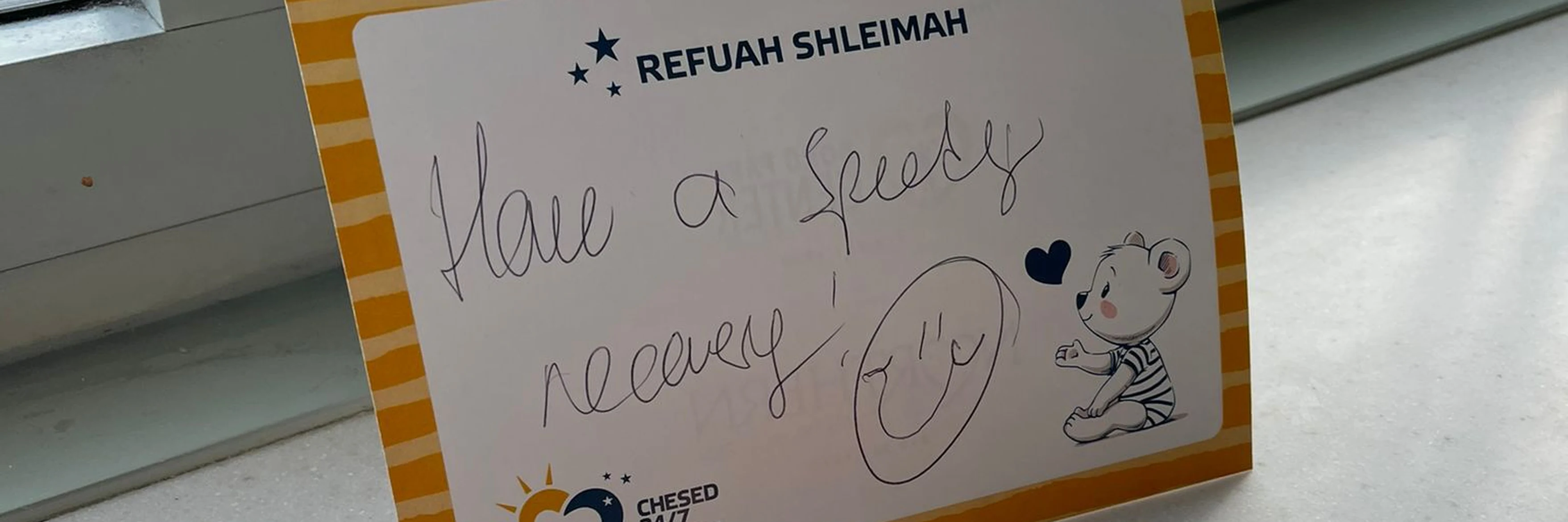 Chesed 24/7 gift package with get-well card and comfort items on a hospital windowsill