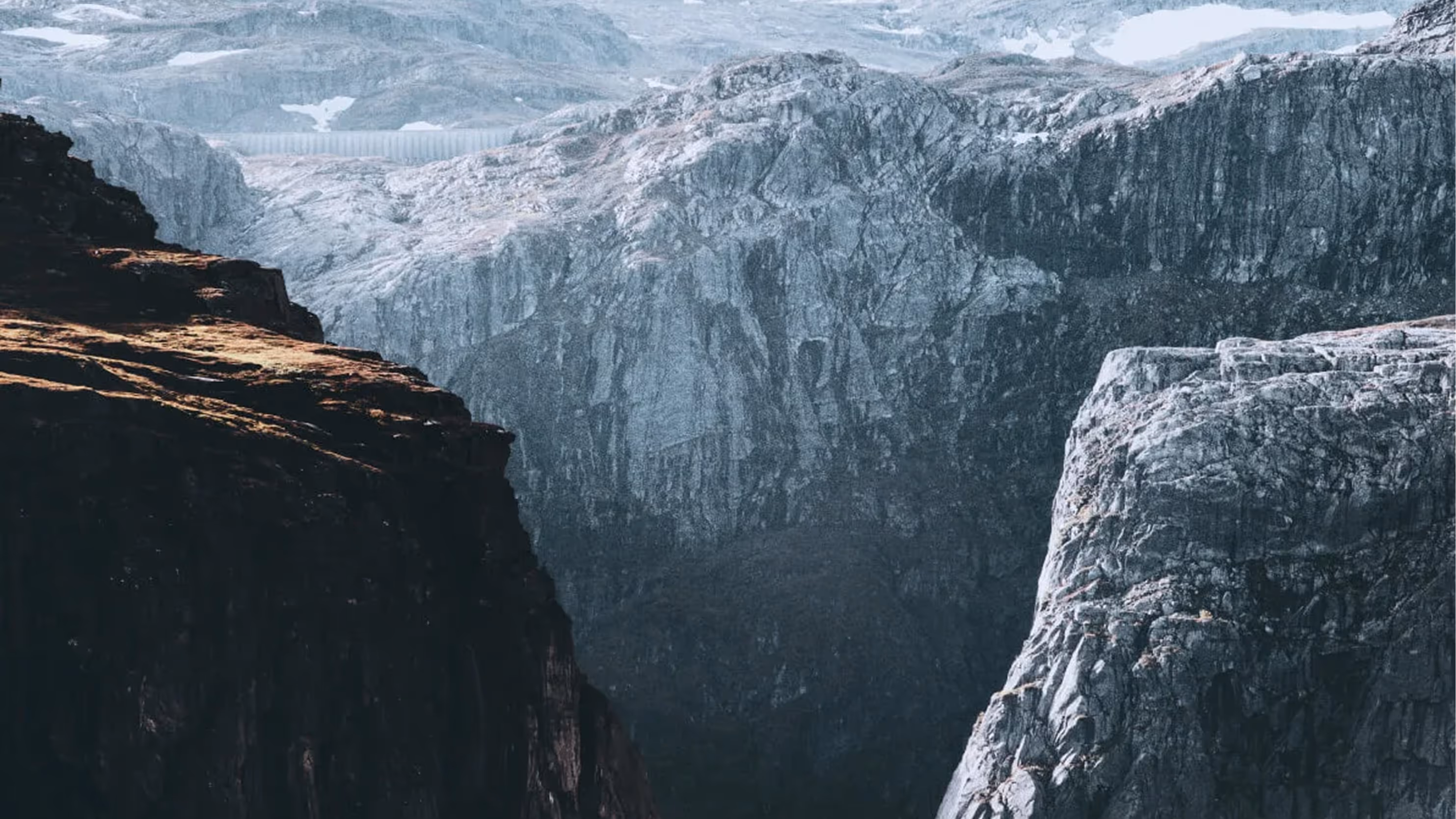 Steep rugged mountains with rocky cliffs under a cloudy sky.