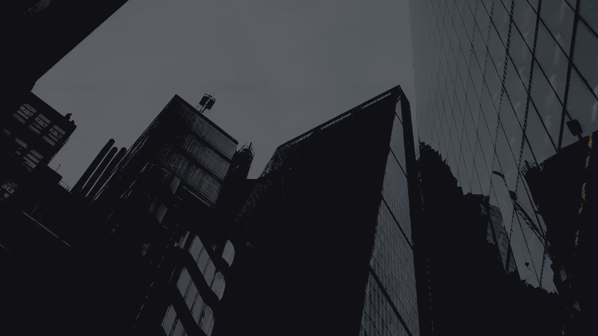 Low-angle view of modern glass skyscrapers against a dusky sky.