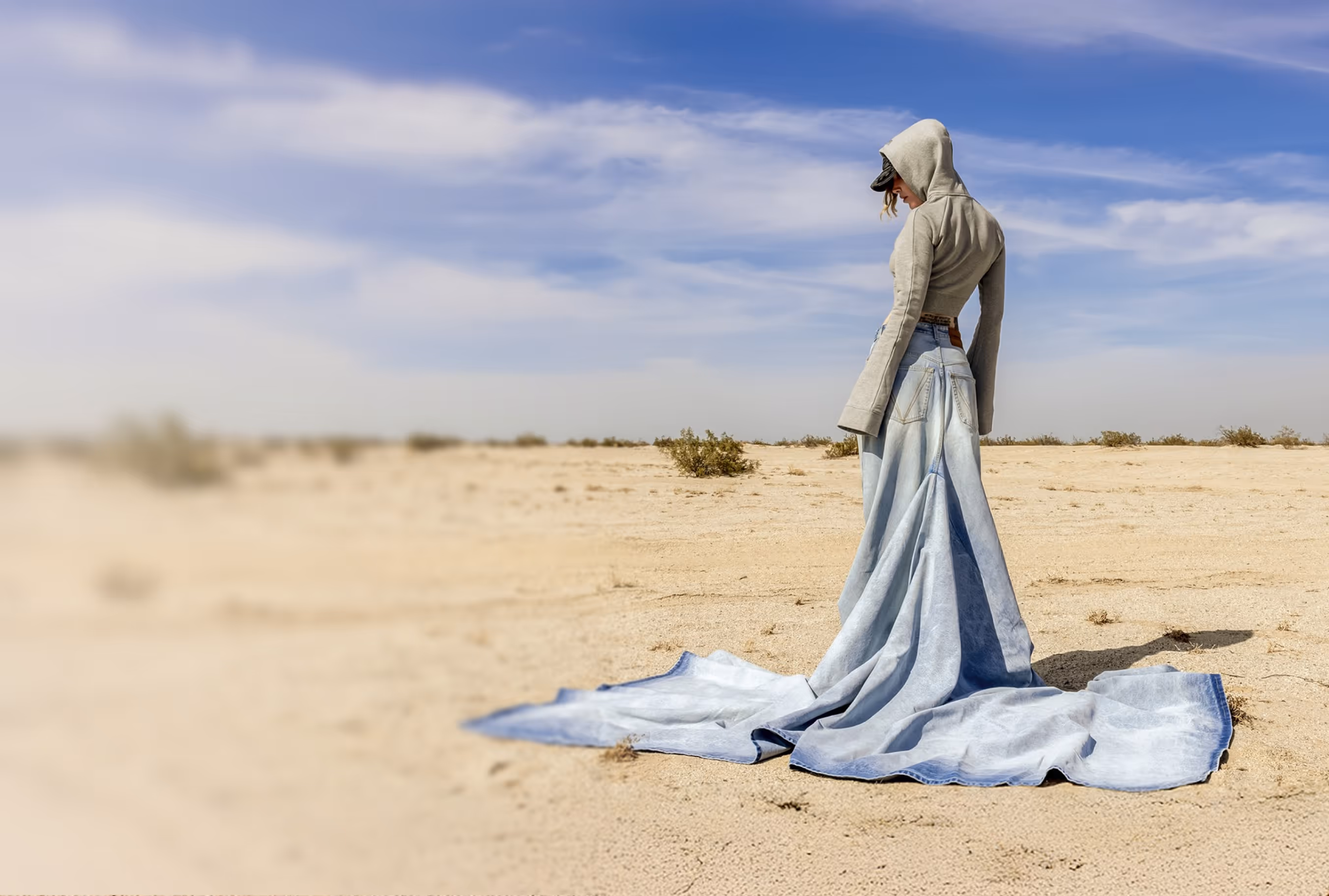 Model in denim outfit with a hat and backpack on grass field