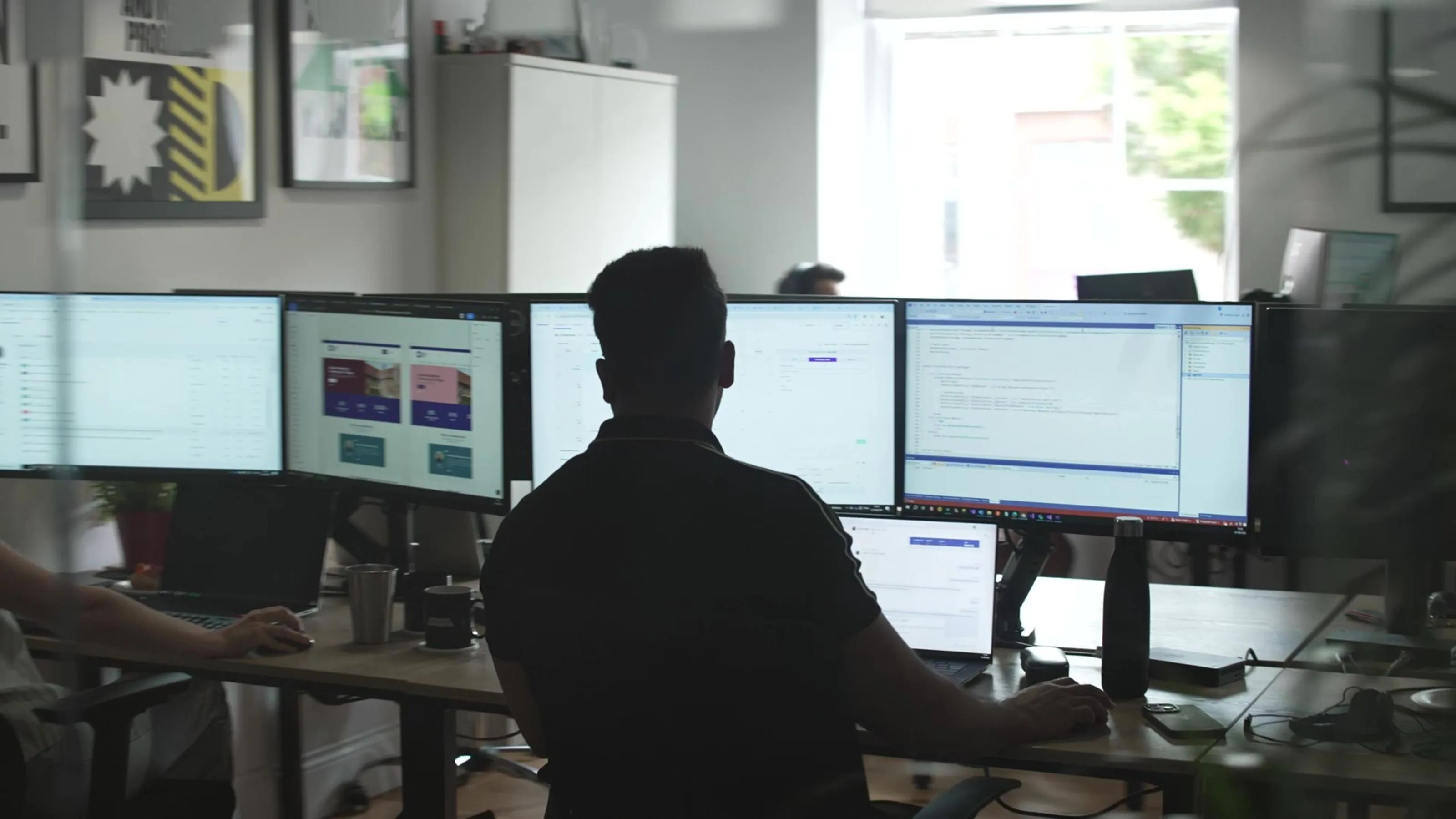 Photograph of team member using multiple screens on their computer.