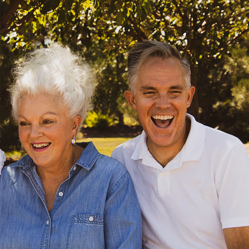 Smiling elderly woman beside a laughing middle-aged man. Clean Slate Clinic clients.