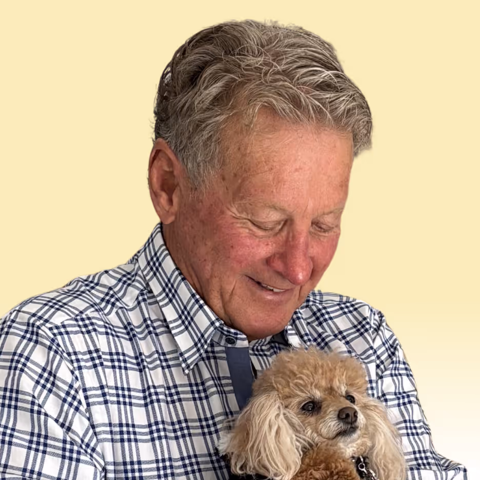 Smiling elderly man holding a small fluffy brown dog. Clean Slate Clinic client.