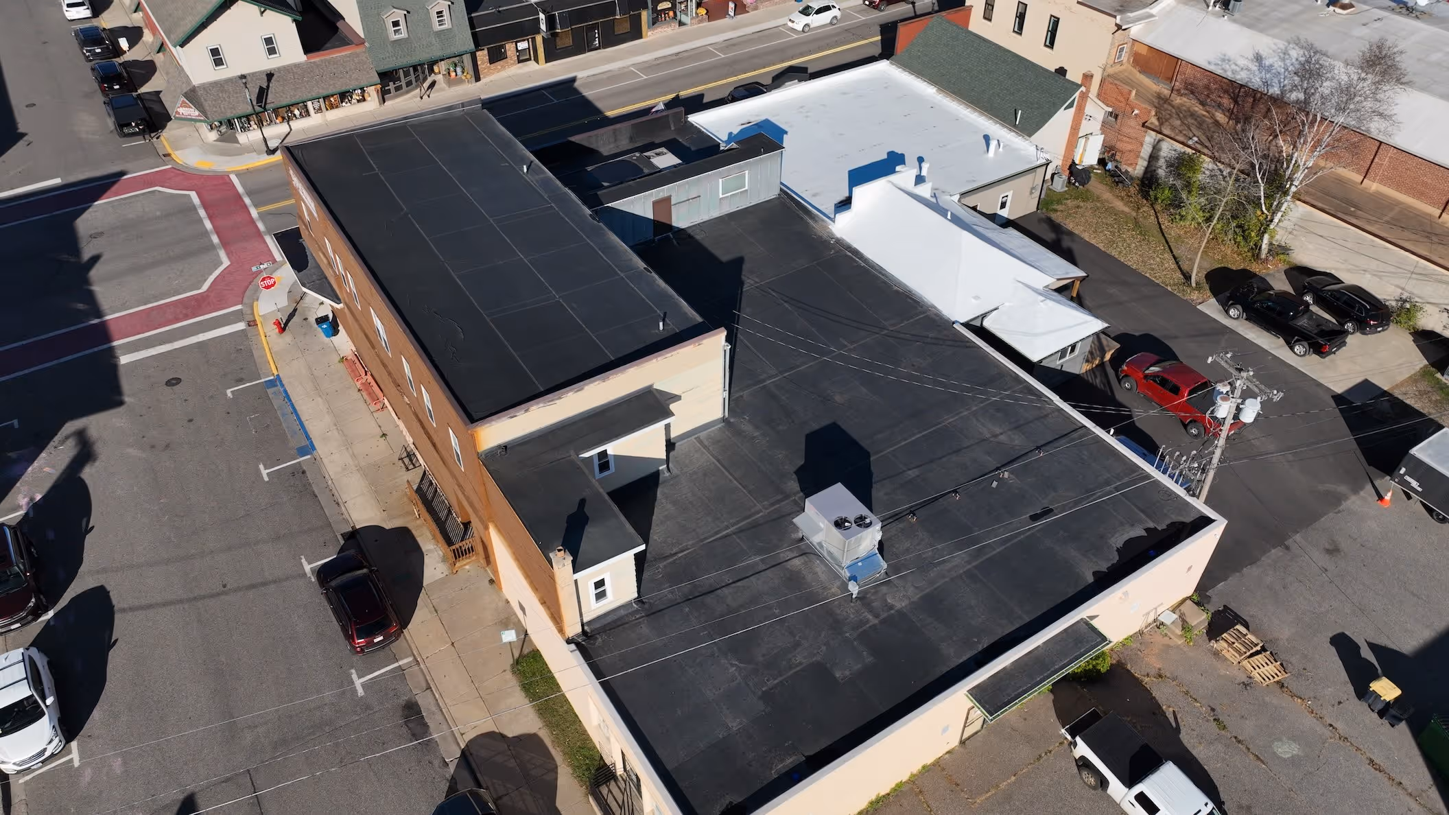 Aerial view of a town block showing flat rooftops, parked cars, and a stop sign at a street corner.