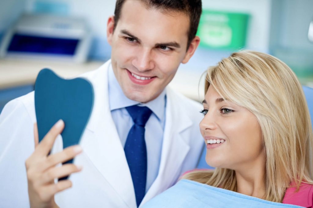 woman checking herself in the mirror with cosmetic dentistry in 33301