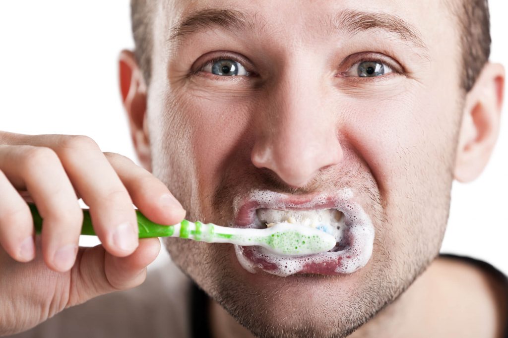 man brushes teeth to prolong teeth whitening in Plantation, FL