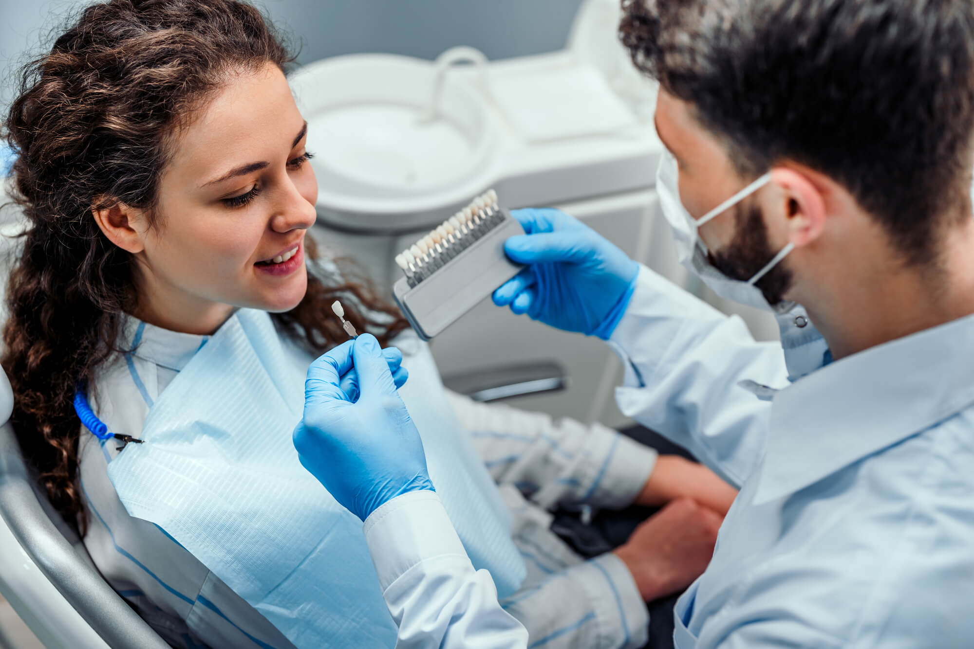 dentist helping patient choose the shade for her Dental Crowns Davie, FL