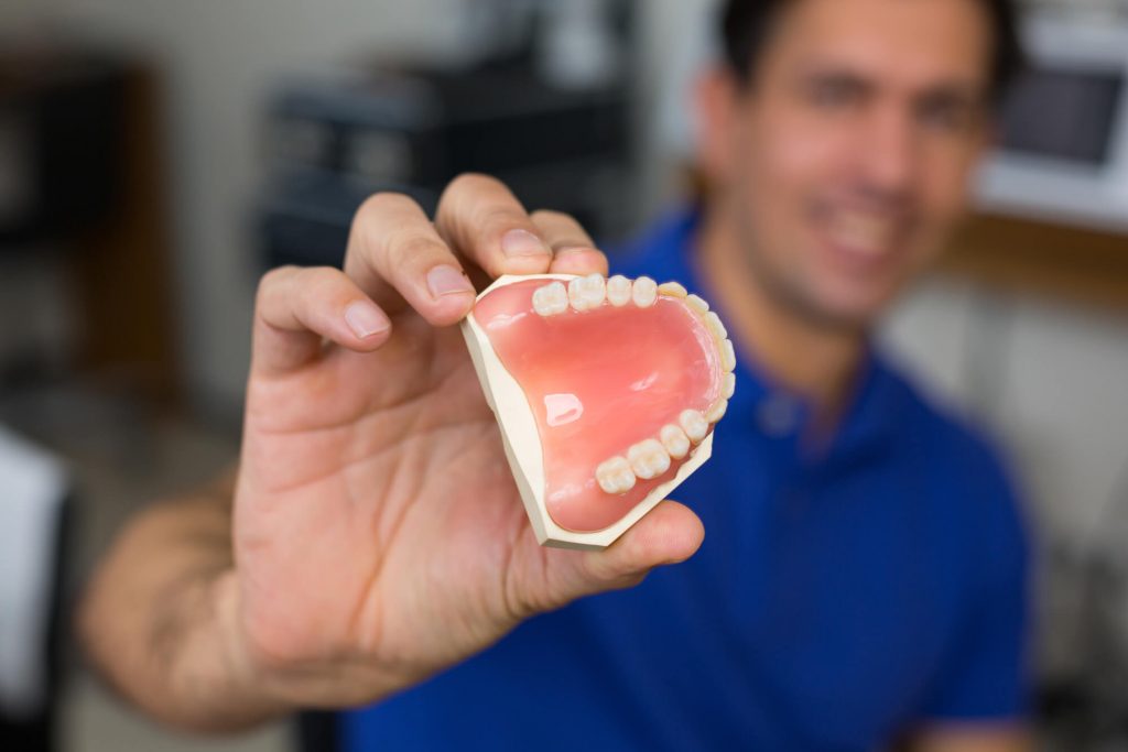 dentist shows teeth model in course of explaining implants in 33317