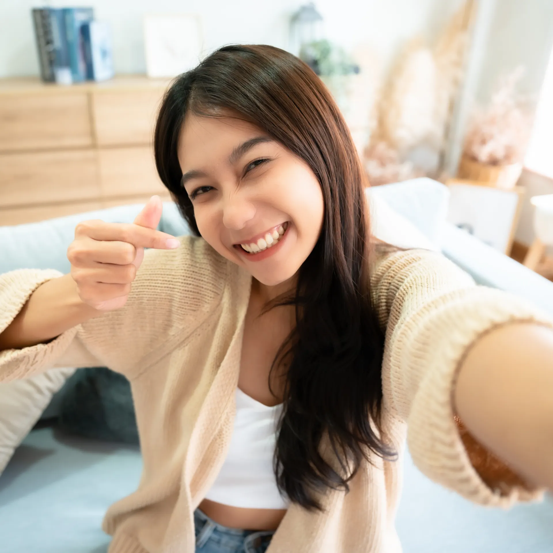 A woman is smiling and pointing at the camera.