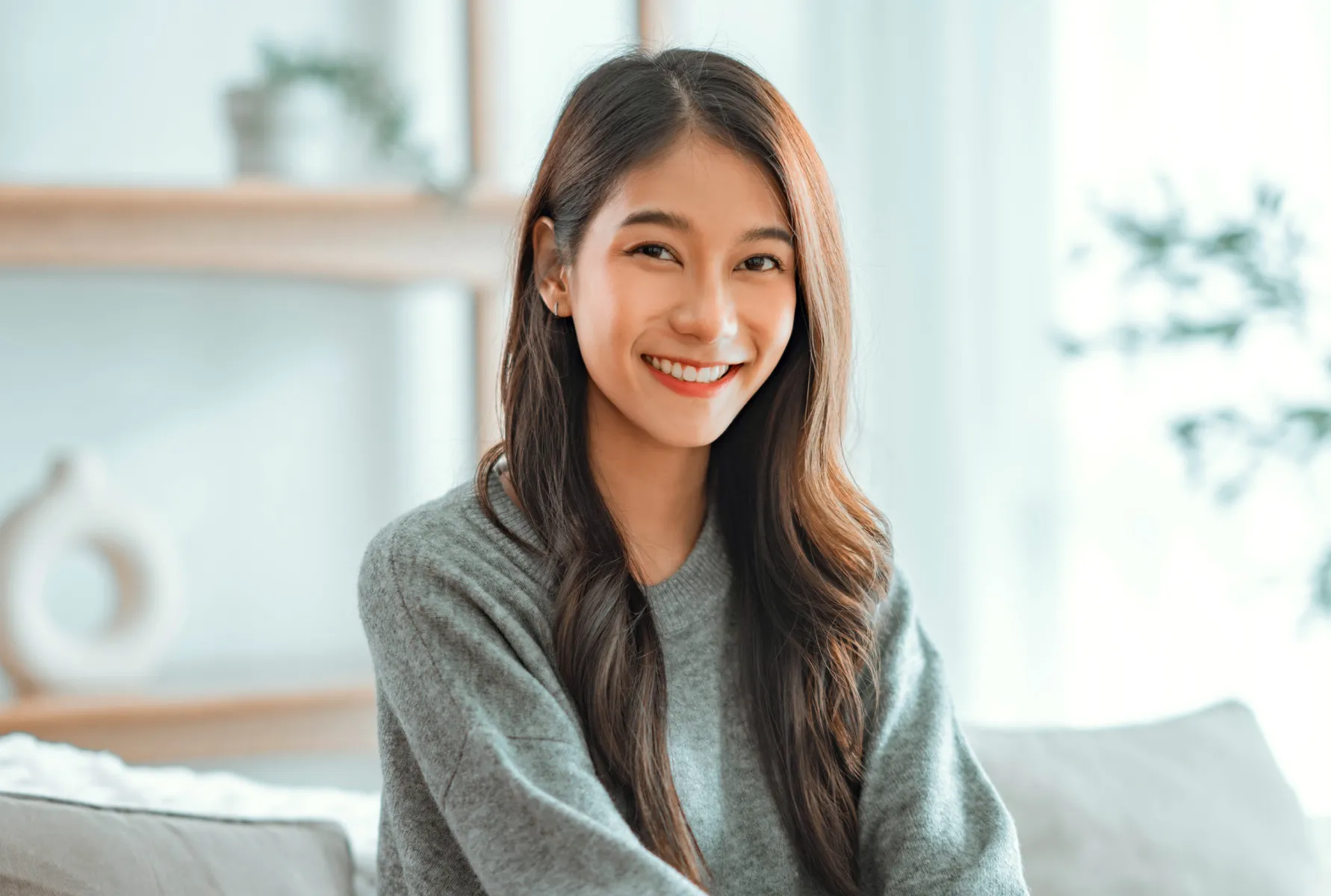 A woman sitting on a couch smiling at the camera.