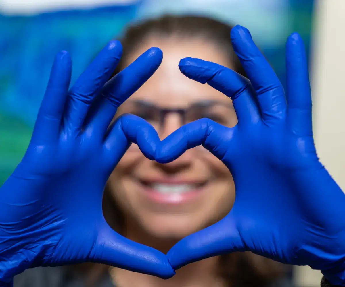 woman wearing blue gloves, making a hearth with her hands