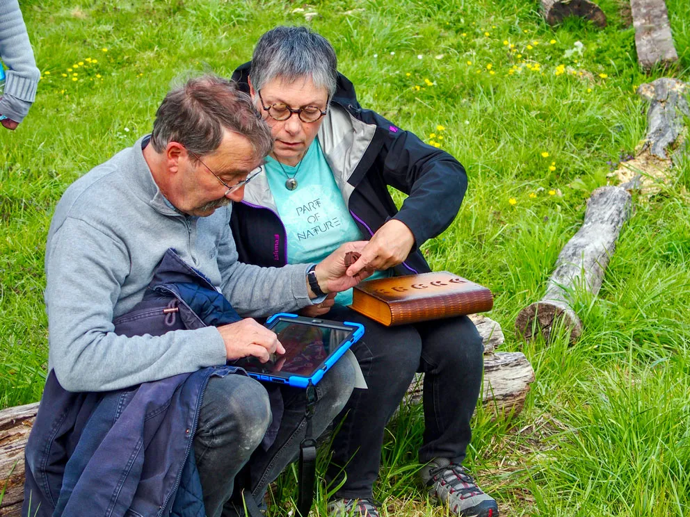 Deux personnes jouent un escape game à domicile, sur une tablette.