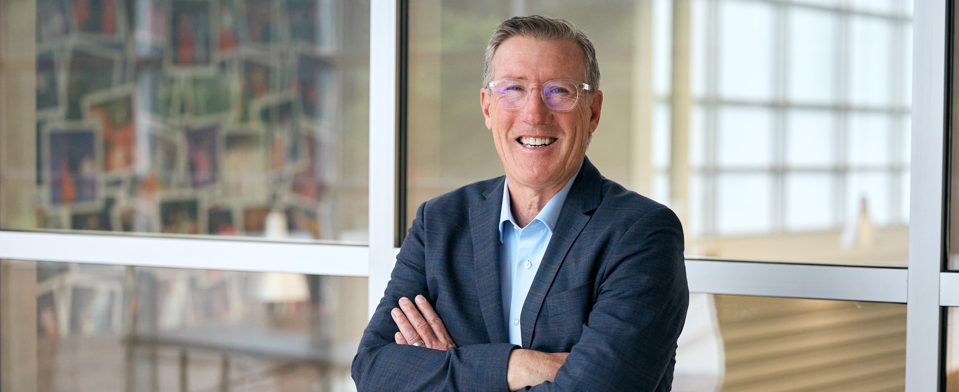 Kelly standing with arms crossed in front of a glass wall.