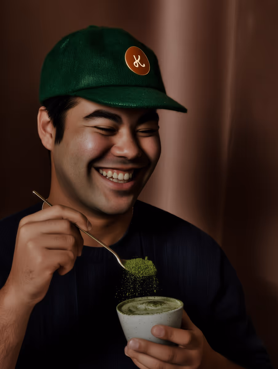 A man with a cap is enjoying a cup of green matcha tea.
