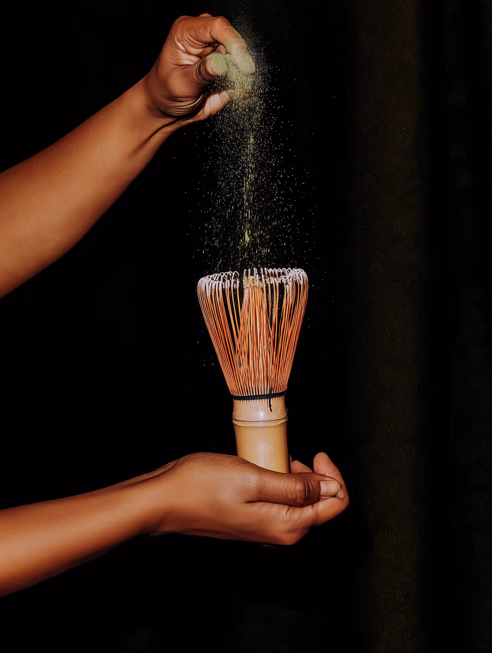 Hand is holding a ceremonial matcha whisk for tea preperation.