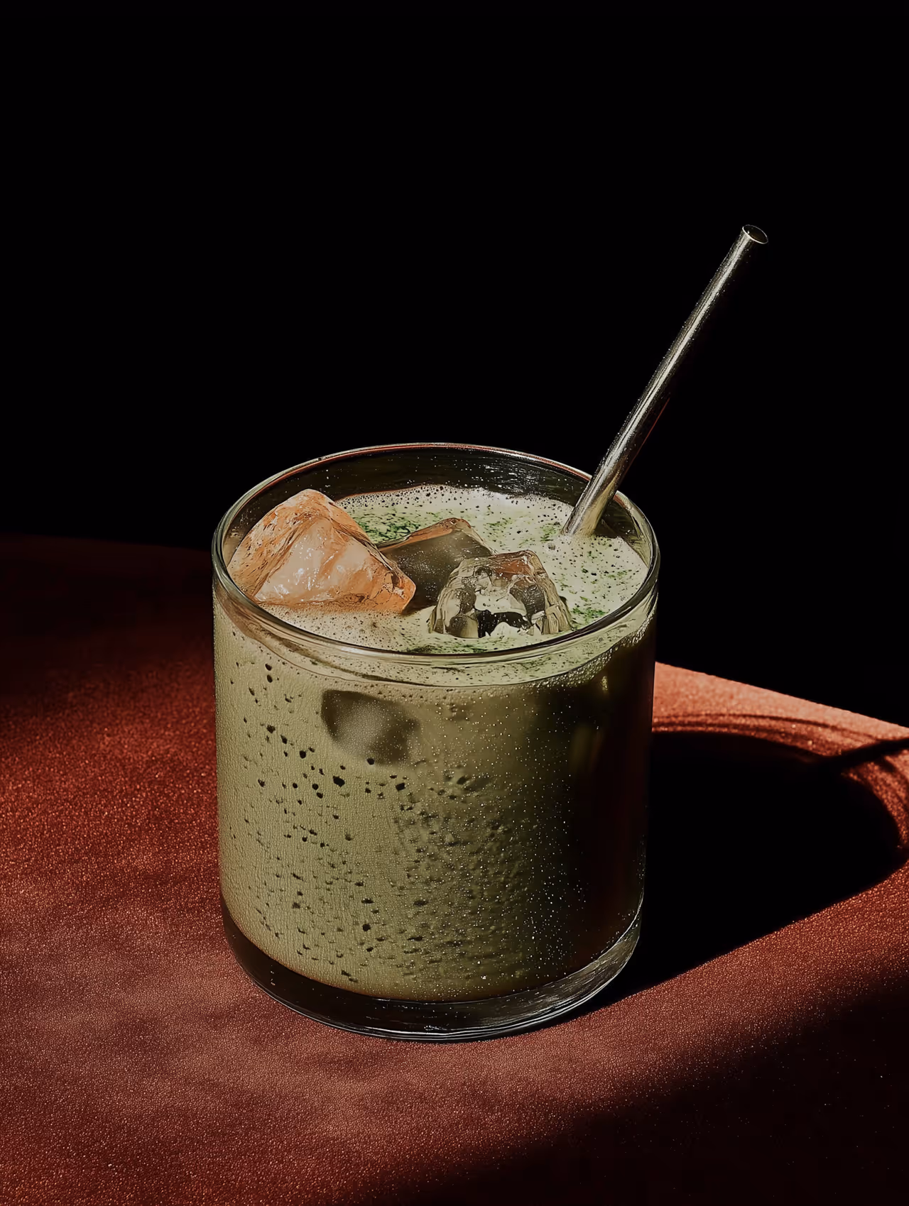 Green iced Matcha in an elegant glass with a straw.