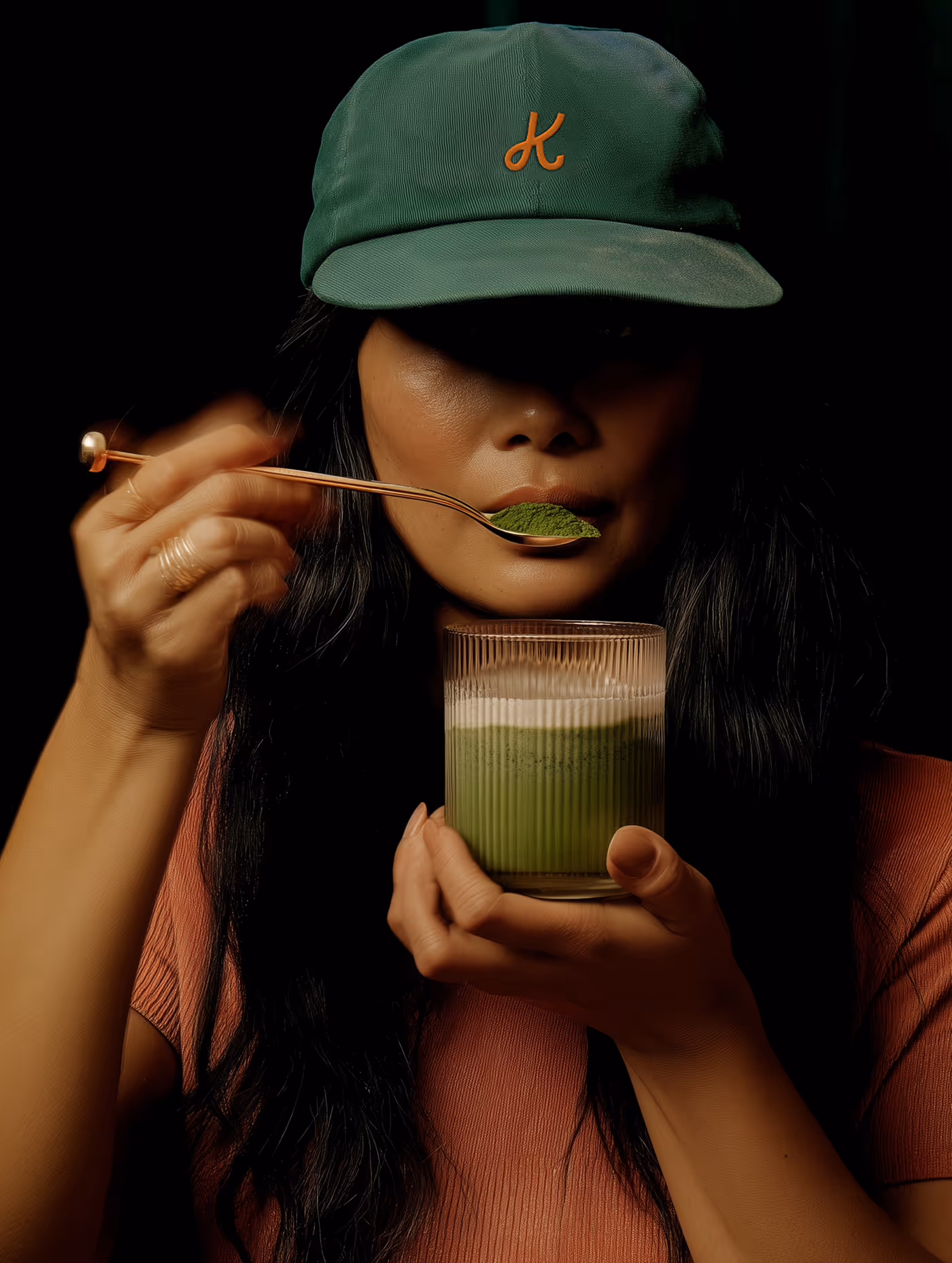 Young Woman is drinking a matcha latte with a spoon from her glass.