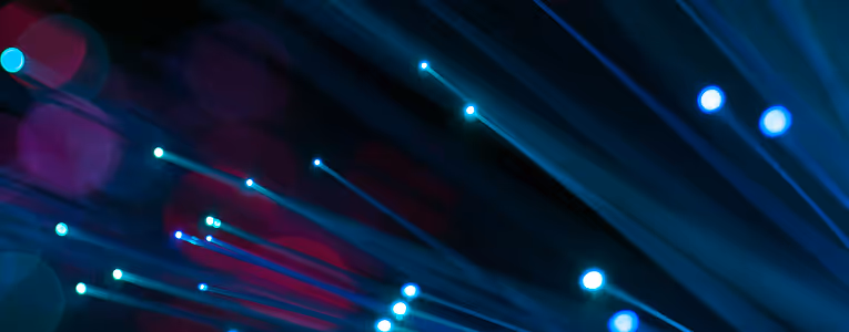 Close-up of glowing blue fiber optic cables with light streaks on a dark background.