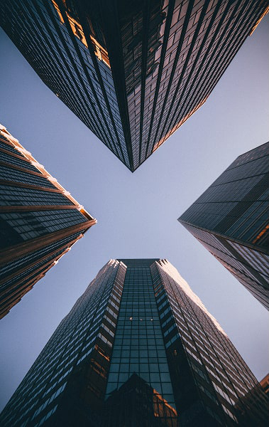 Looking up at four tall modern skyscrapers against a clear blue sky.