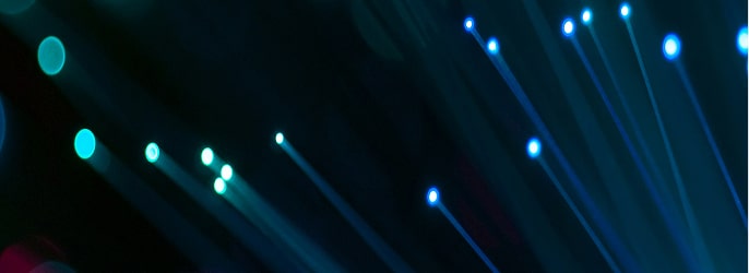 Close-up of glowing fiber optic strands emitting blue and teal light against a dark background.