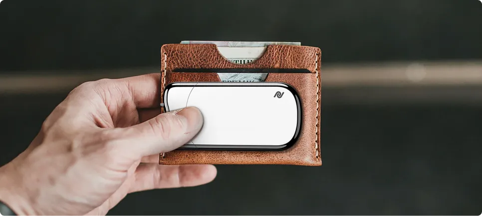 Hand holding a refined white pocket device in a leather wallet — finished product design