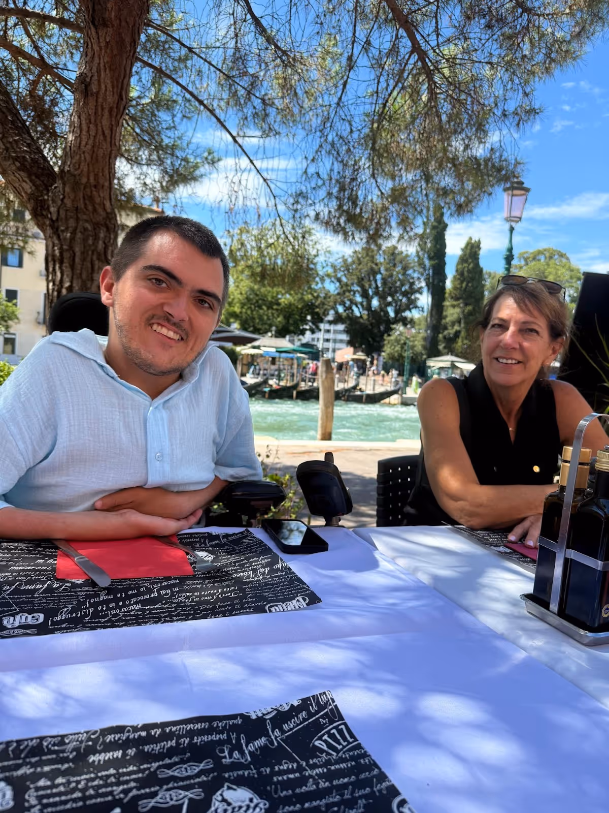 A man and woman sitting at a table with the Venice canal behind them