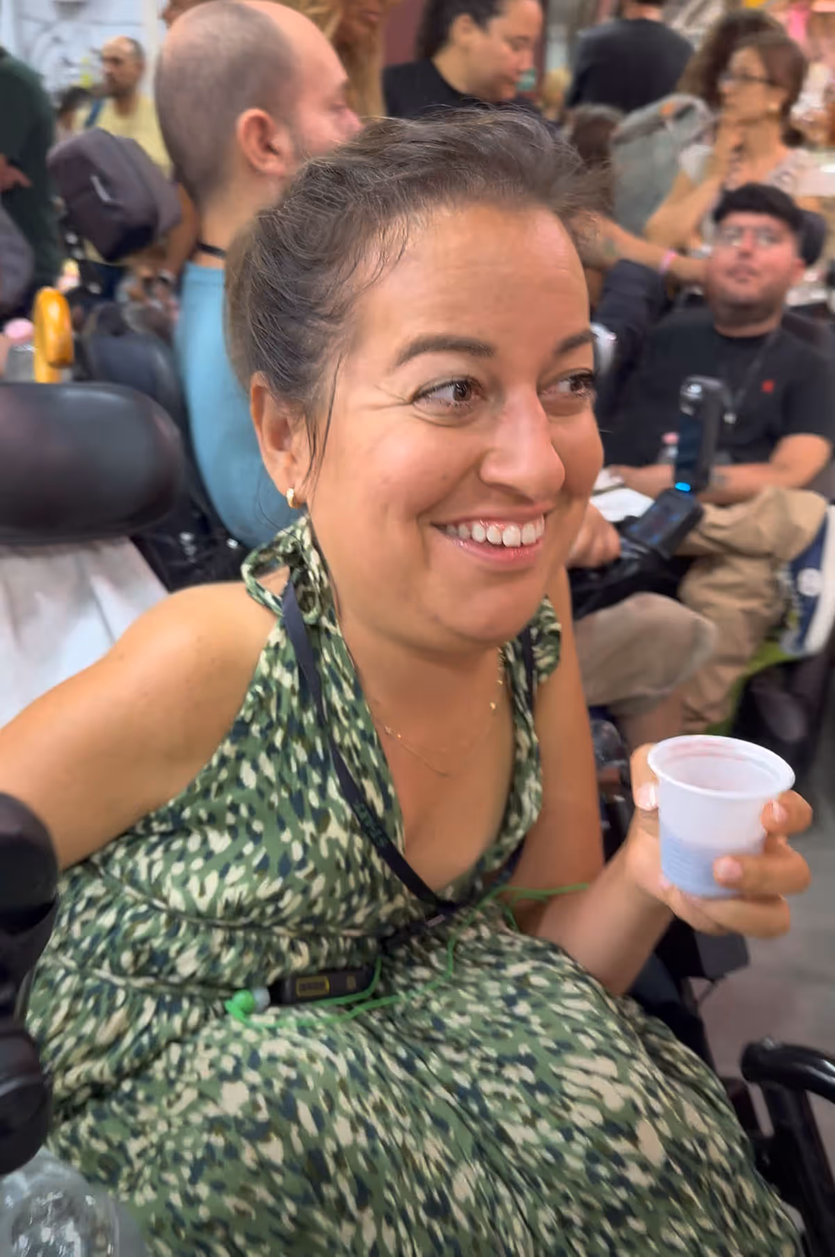 woman wearing a green dress smiling and holding a plastic cup of wine