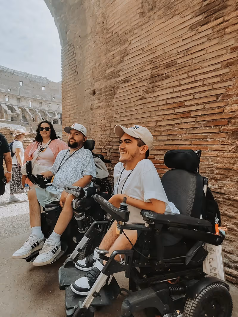 Three people listening to the tour guide inside the Roman Colosseum