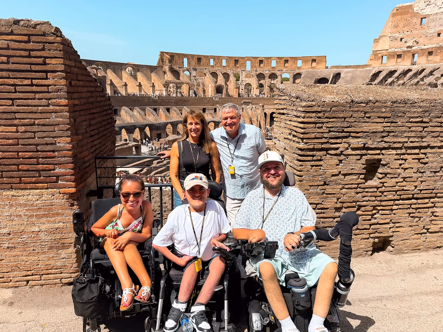Family with two people standing and three people in wheelchairs inside the Roman Colosseum
