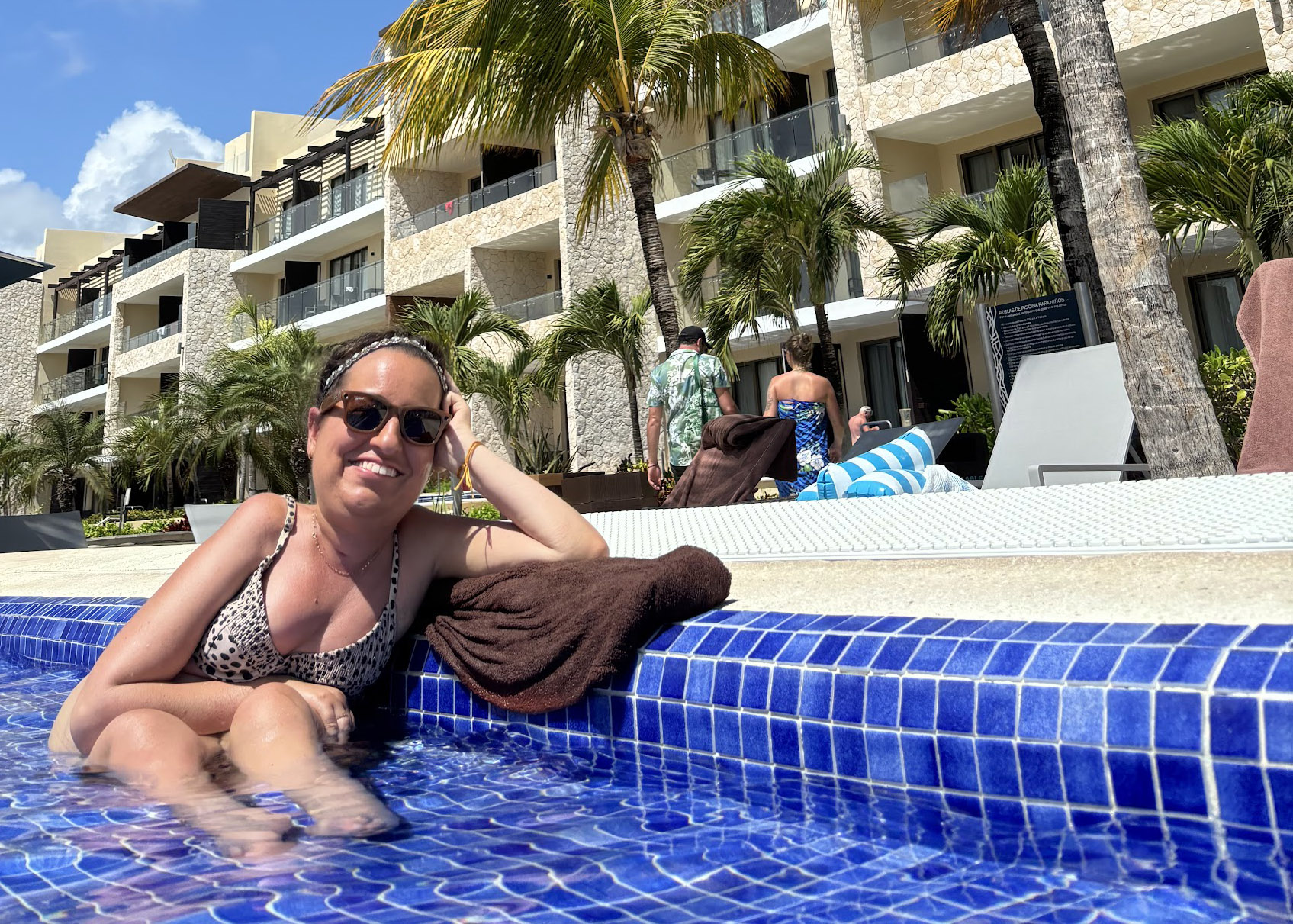 Woman relaxing at the edge of a resort pool at Royalton Riviera Cancun