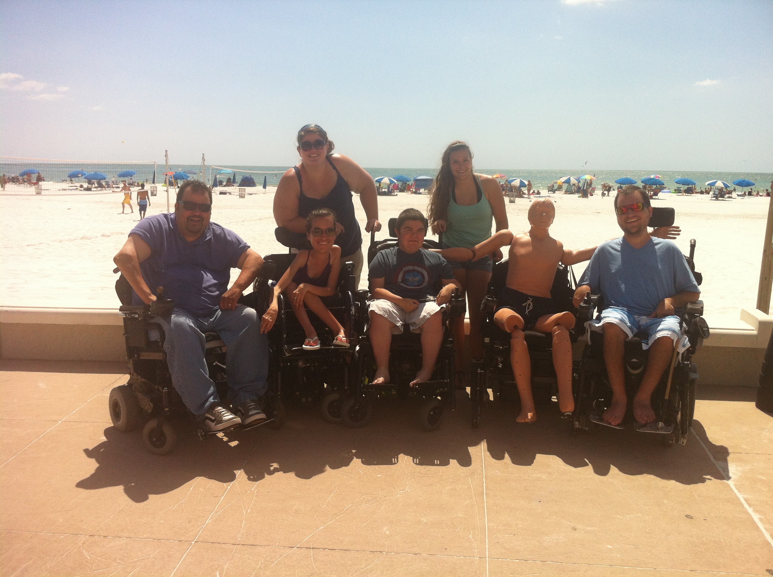 Group of wheelchair users and friends posing together on a beach trip to Clearwater Beach