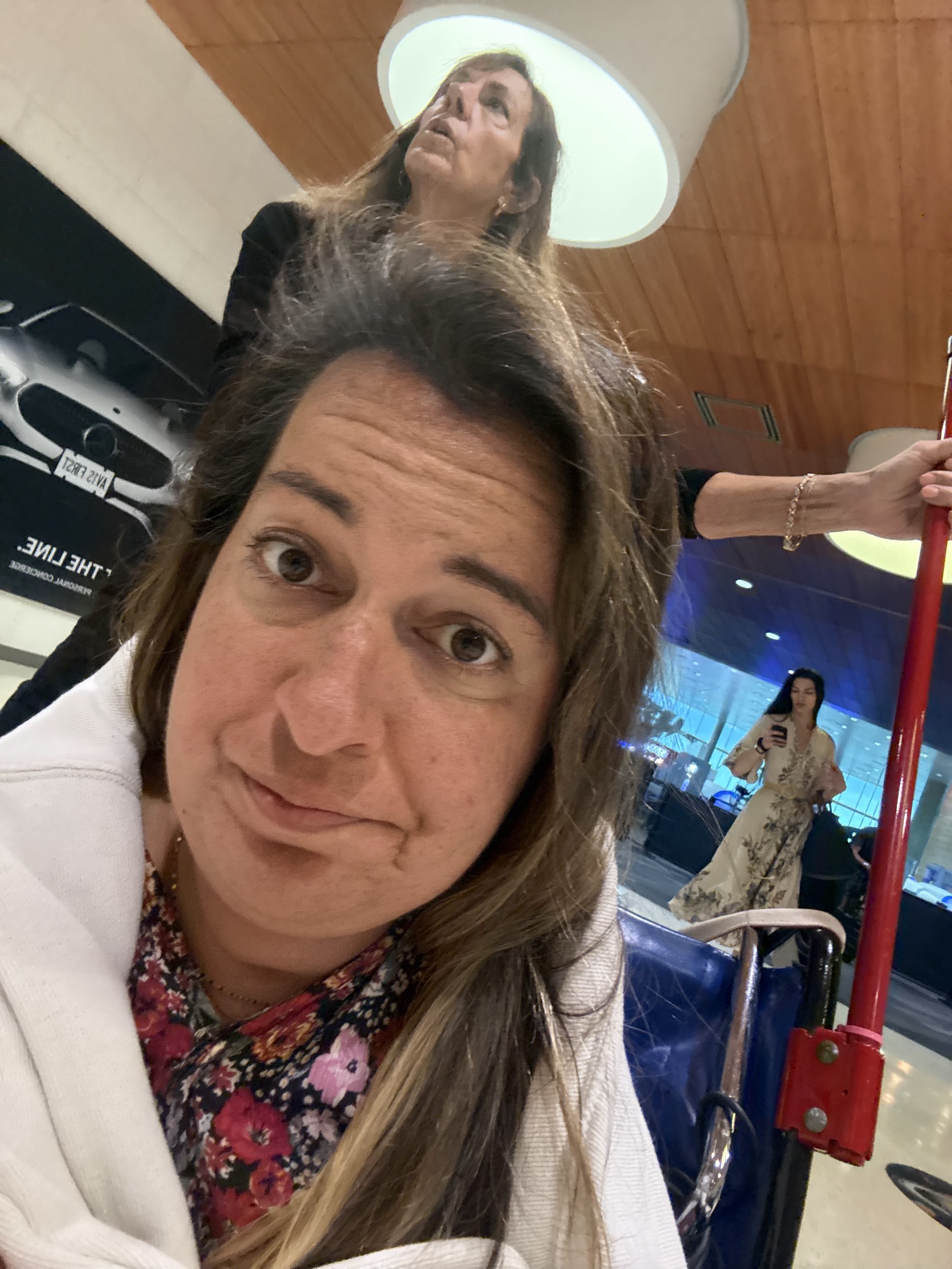 Girl with sweater around her looking sad in an airport wheelchair